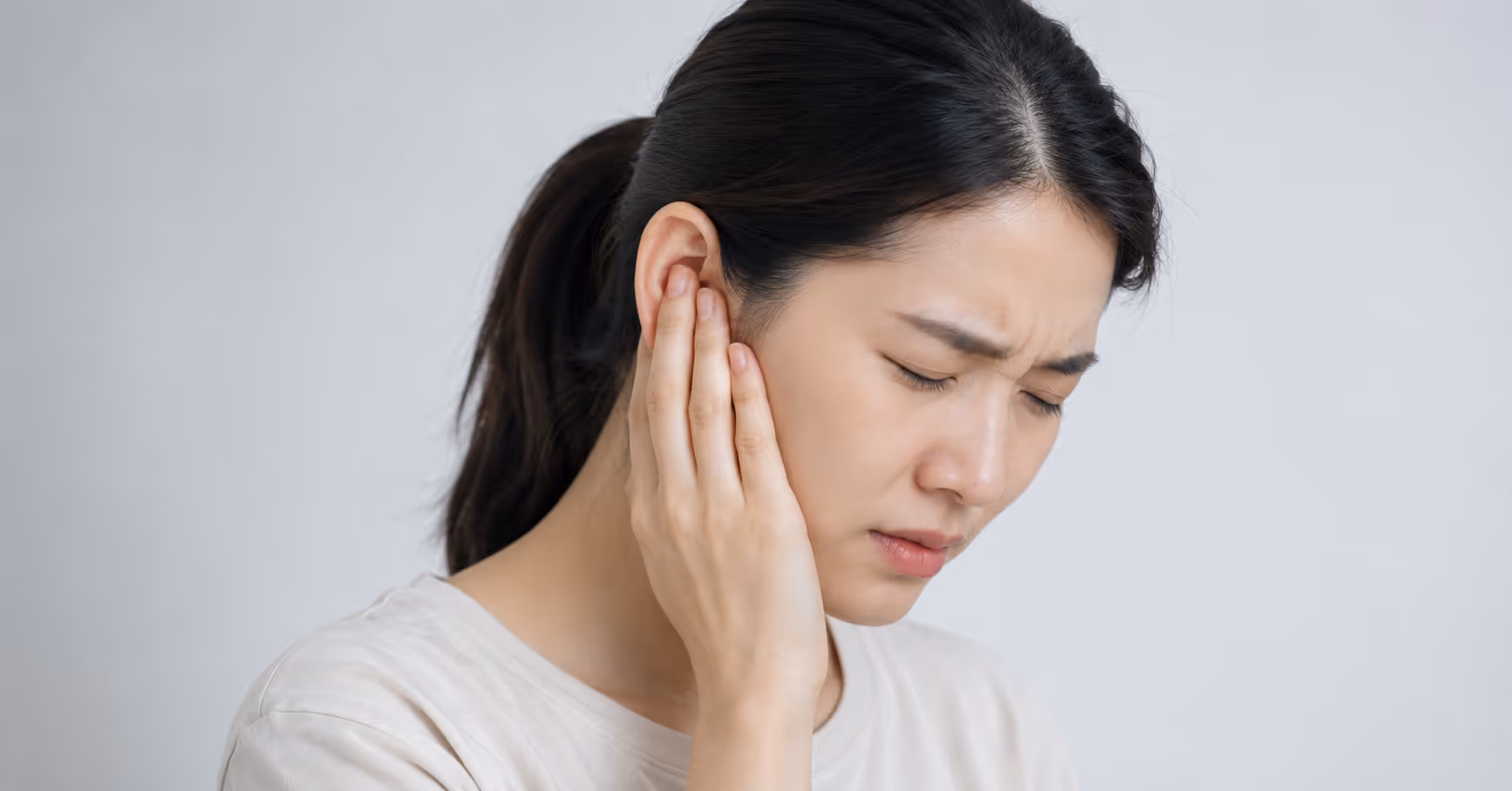Woman experiencing hearing loss associated with Streptococcus suis infection (deafness fever), holding her right ear.