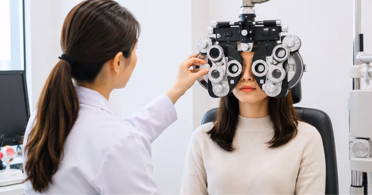 Visual Acuity Test: An ophthalmologist is performing an eye exam on a woman using a device called a phoropter in an examination room.