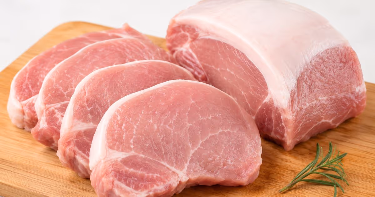 Raw pork meat placed on a cutting board before cooking, a potential source of Streptococcus suis infection if improperly handled or undercooked.